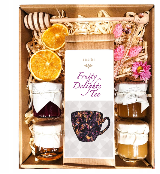 Geschenkkorb mit Blumen, Honig, Tee und Marmelade.